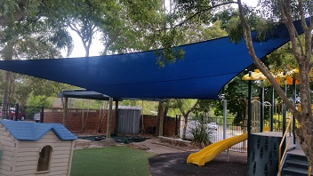 A blue custom made shade sail covering play area for a childcare located in Brisbane